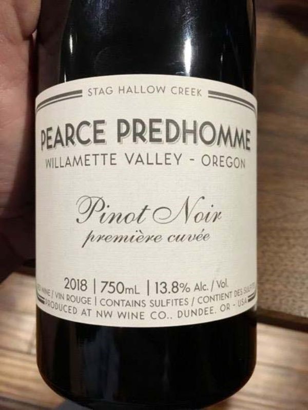 A home photo of a bottle of wine in a Caucasian man's hand, the label reads: 

Stag Hallow Creek
Pearce Predhomme
Willamette Valley - Oregon
Pinot Noir - première cuvée 2018

750mL, 13.8% Alc/vol.